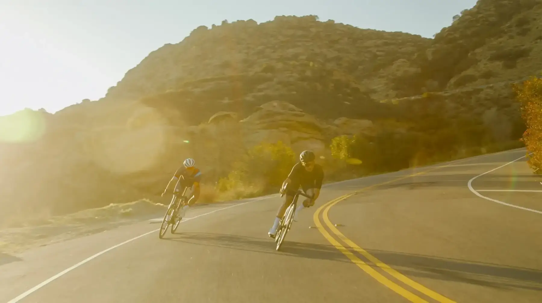 Cyclists descending a mountain road at sunrise